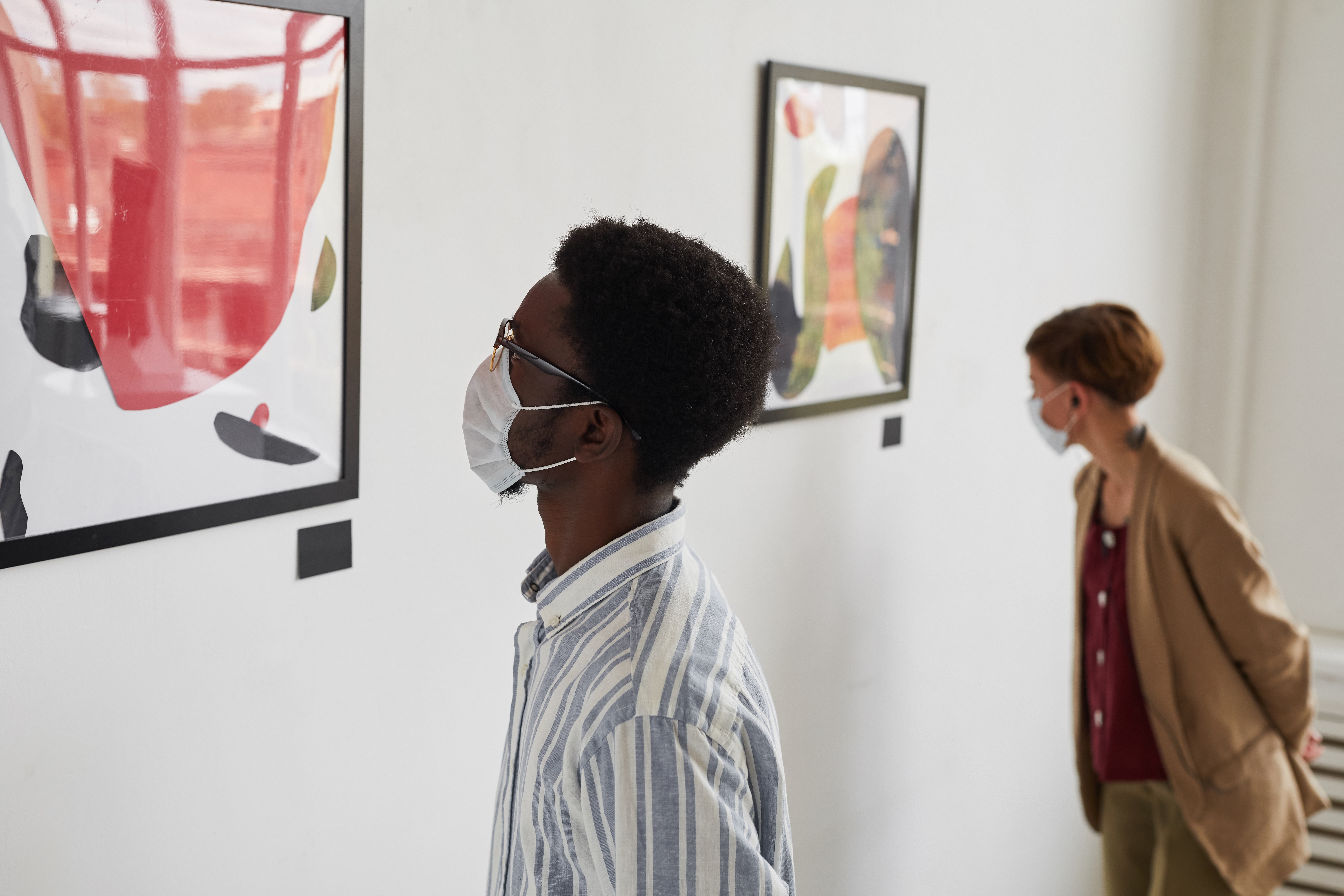 People wearing masks looking at paintings in a gallery