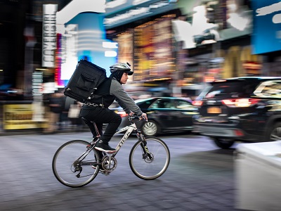 A bicycle courier cycling through a city