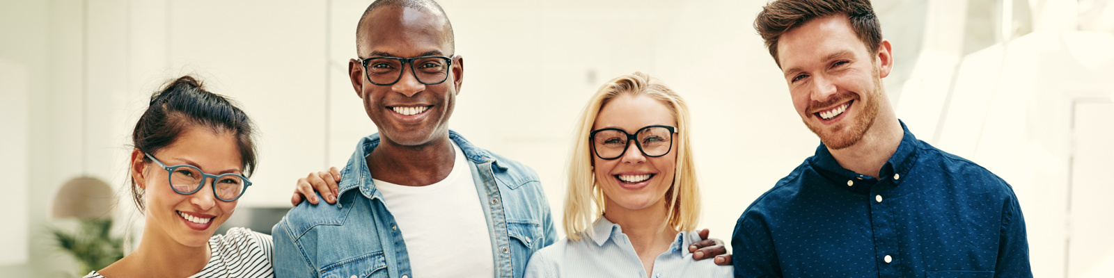 Smiling group of young businesspeople standing in an office.