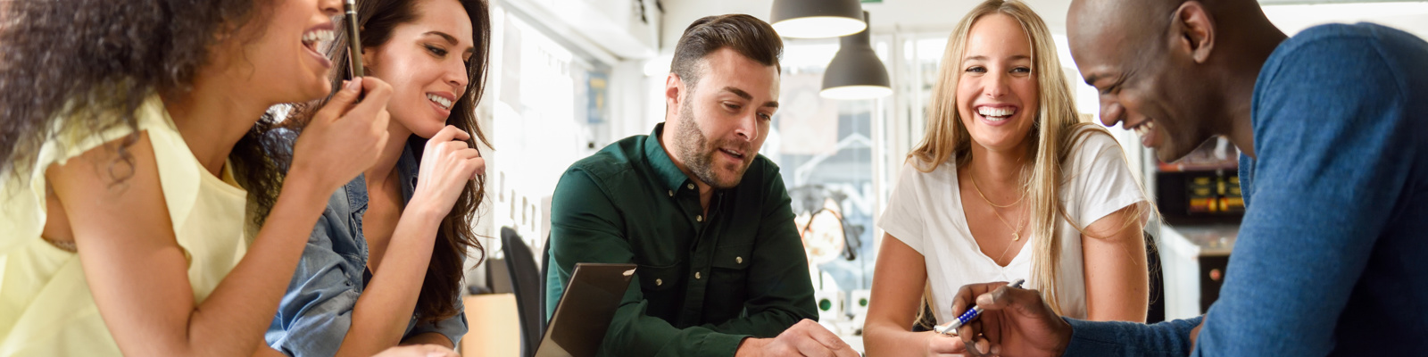 Creative modern young business colleagues searching for some new ideas while sitting in a coffee shop. Looking at laptop and chatting