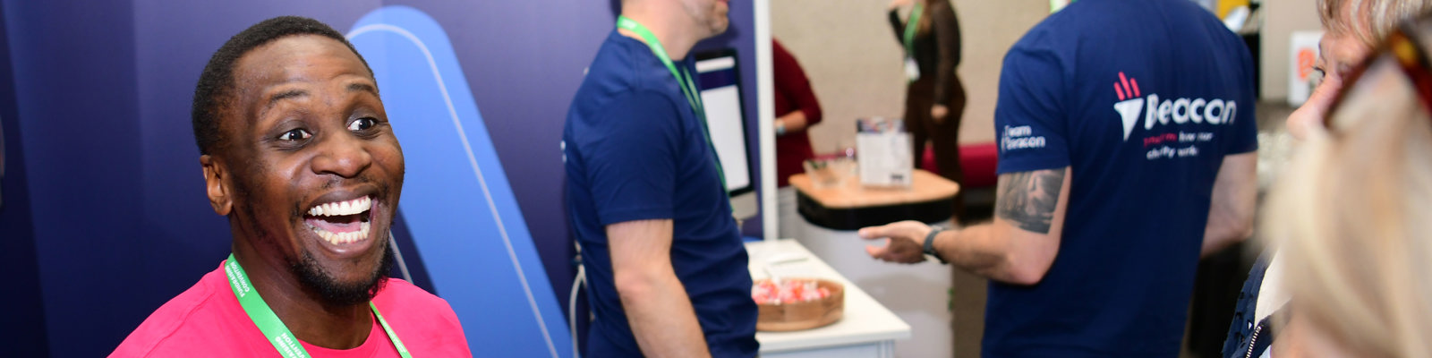 Photo of Beacon sponsor and exhibitor employer at Fundraising Convention smiling and talking to delegates.