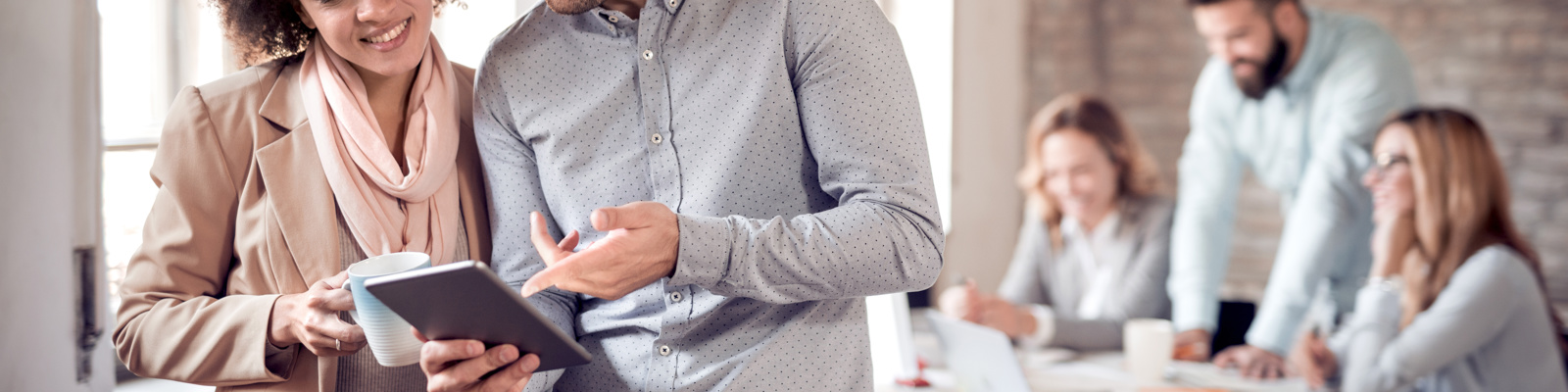 Business colleagues in modern office using tablet smiling and reading a report.