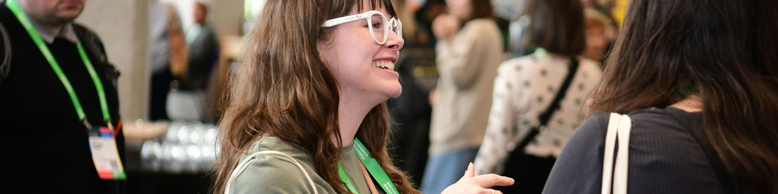 Photo of a delegate wearing glasses stood talking to another delegate at Fundraising Convention.