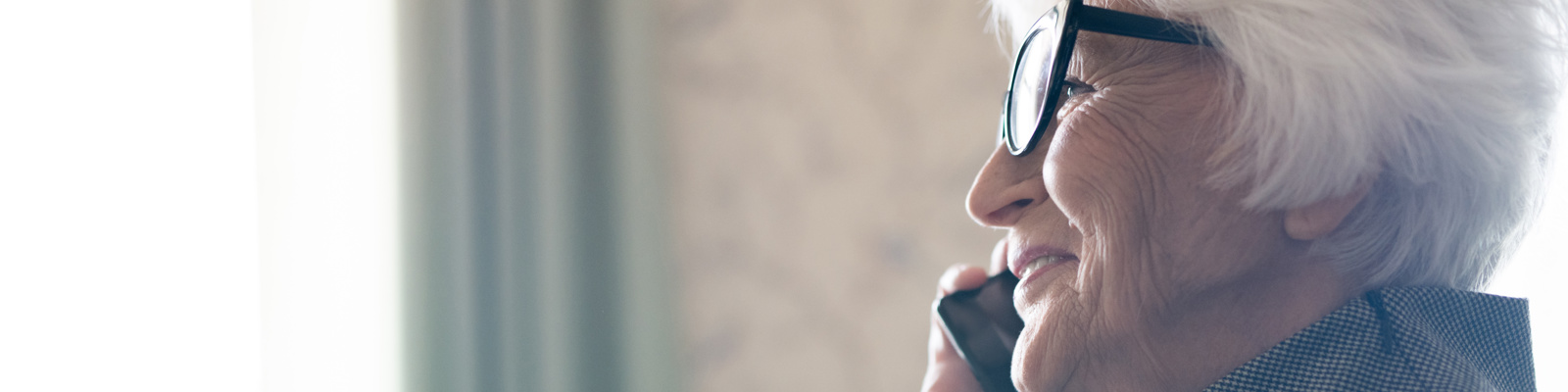 Side view of happy senior woman having a conversation on mobile phone while enjoying a cup of coffee.