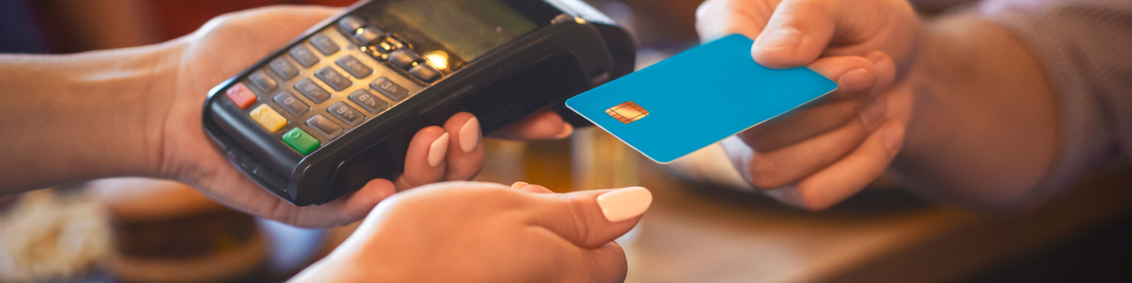 Photo of Person Holding a Card Reader, and Another Hand Tapping Their Card to Donate.