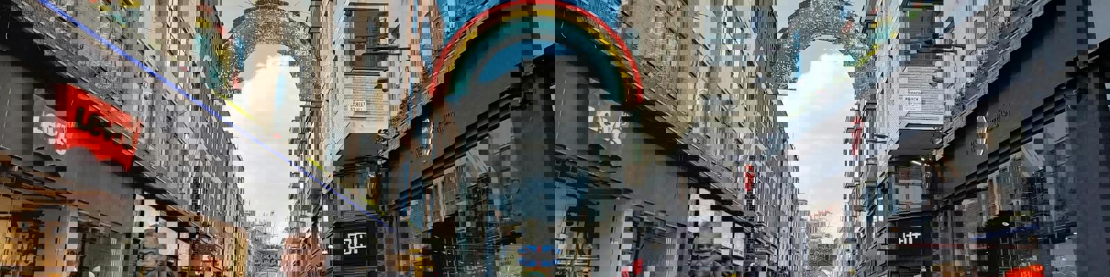 A shopping street in a city, with people walking between shops