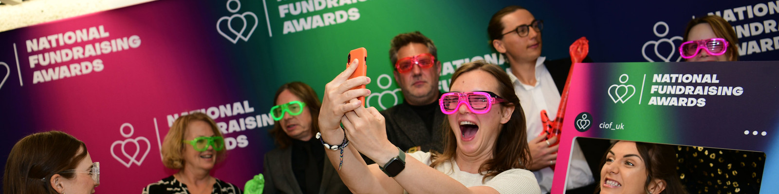 Photo of National Fundraising Awards attendeeds with props taking a selfie in front of the branded step and repeat.