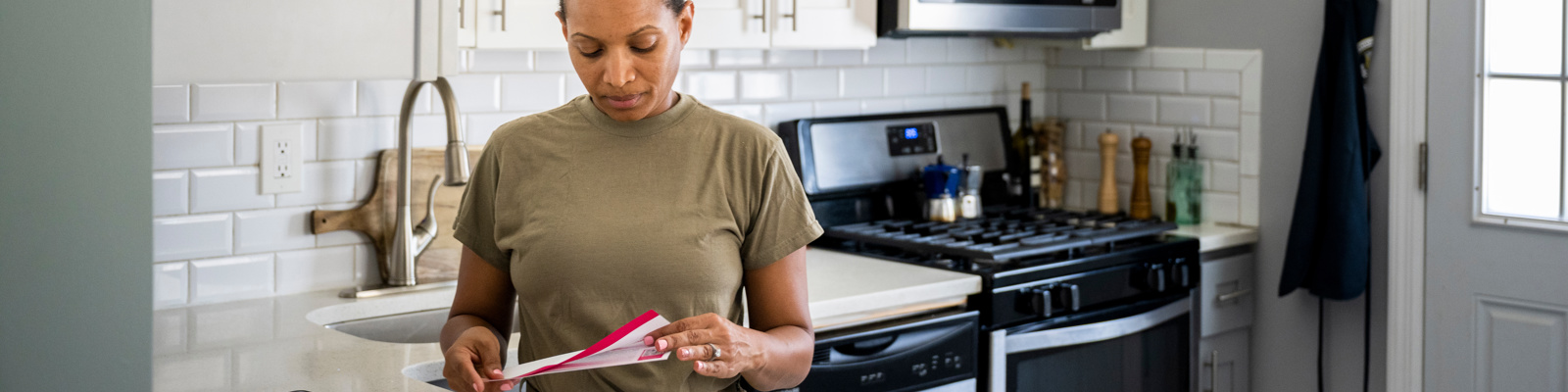Army female soldier opening her mail in her kitchen