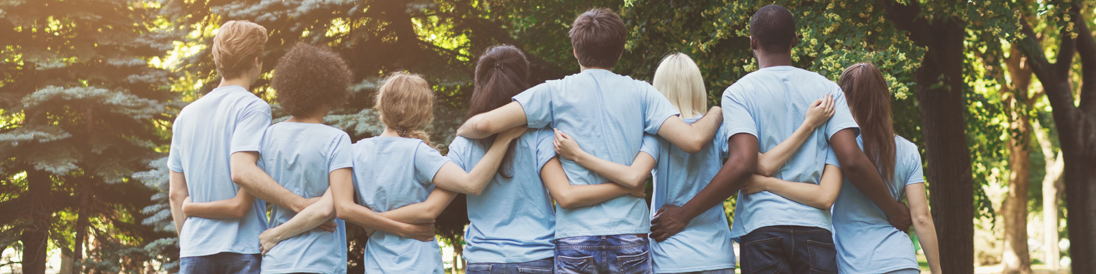 Group of happy volunteers embracing in park