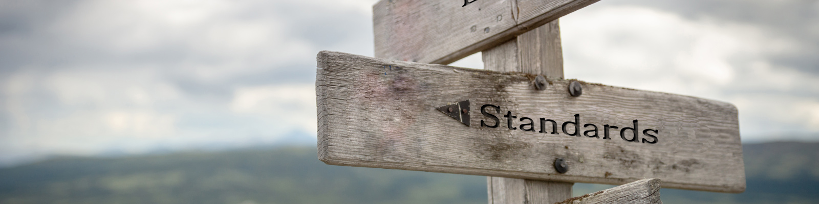 Law, standards and regulations text on wooden road sign outdoors in nature.