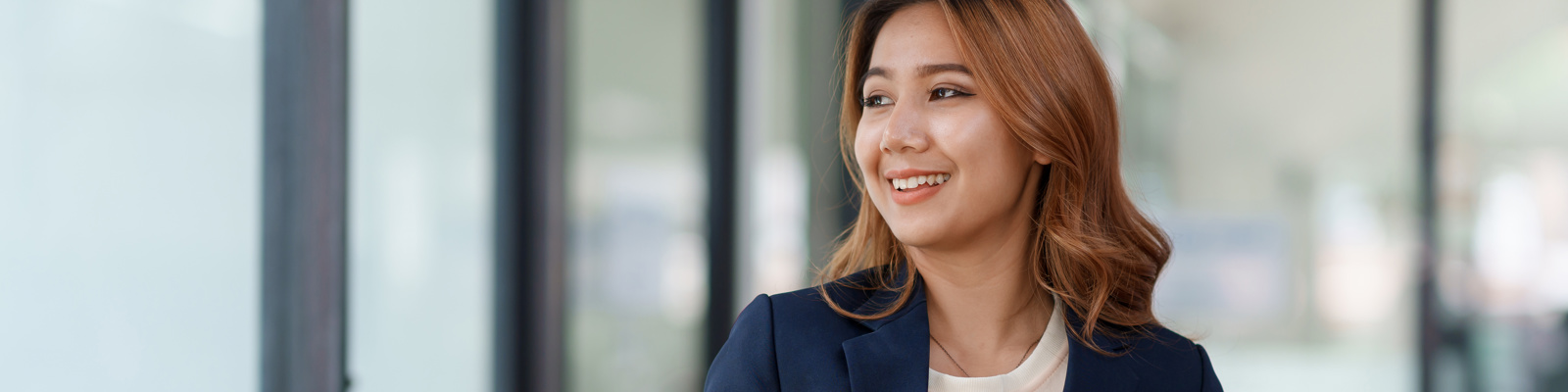 Fundraising professional in a navy blazer holding a tablet and pen, smiling in a bright office setting.
